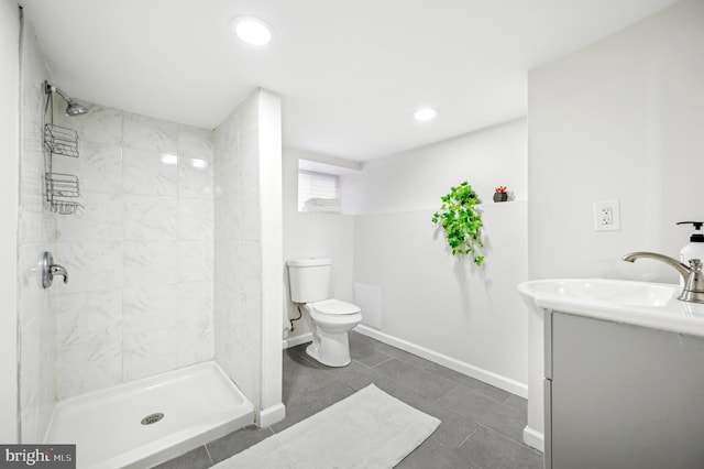 bathroom with tiled shower, vanity, toilet, and tile patterned floors