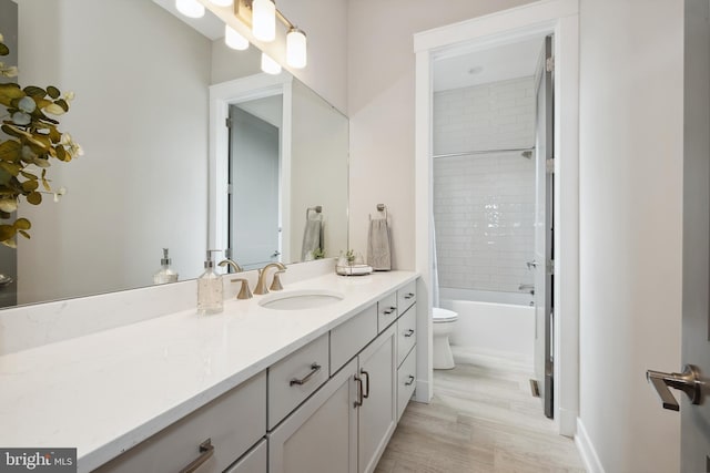 full bathroom featuring tiled shower / bath combo, vanity, hardwood / wood-style floors, and toilet