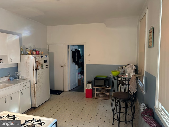 kitchen with white appliances, radiator heating unit, sink, and white cabinets