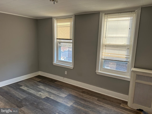 empty room with crown molding, dark hardwood / wood-style flooring, and radiator