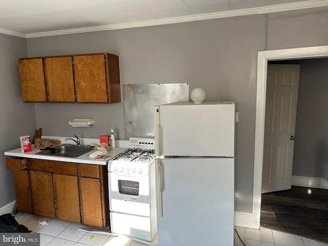 kitchen with crown molding, sink, light tile patterned flooring, and white appliances