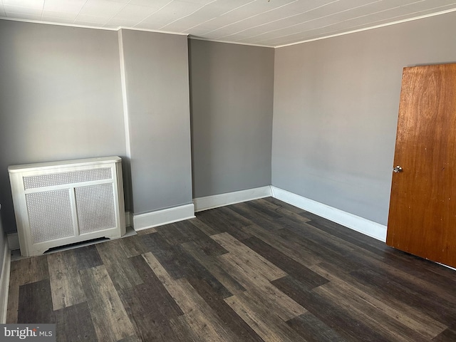 unfurnished room with radiator heating unit and dark hardwood / wood-style floors