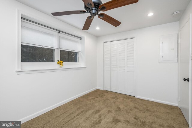 unfurnished bedroom featuring ceiling fan, electric panel, carpet floors, and a closet