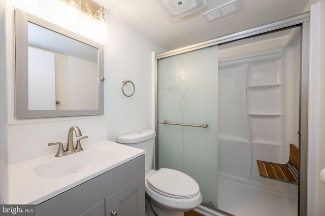 bathroom with vanity, a shower with shower door, and toilet