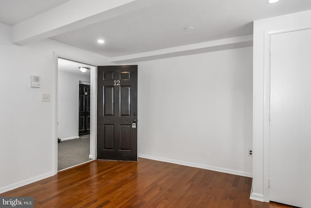 unfurnished room with wood-type flooring and beam ceiling