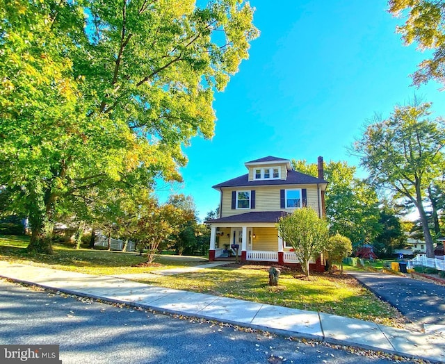 american foursquare style home with a porch and a front lawn