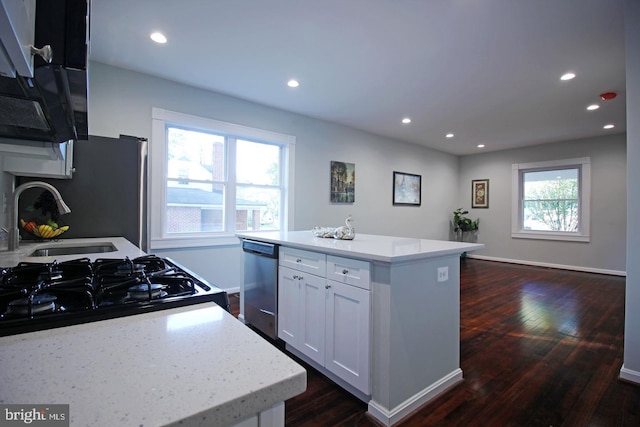 kitchen featuring dark wood-type flooring, stainless steel dishwasher, a center island, and white cabinets