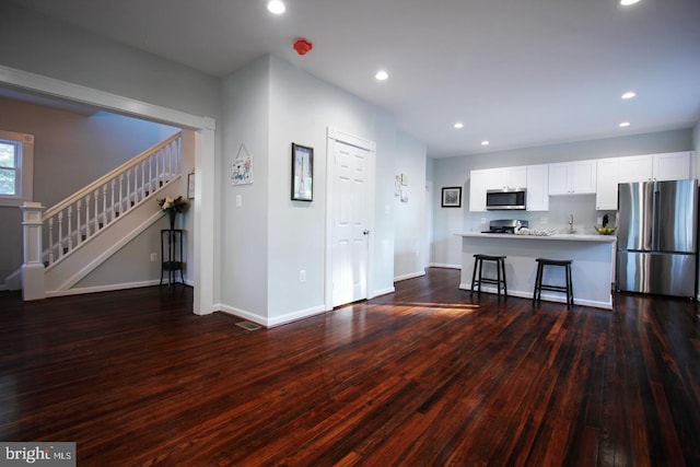 kitchen featuring stainless steel appliances, a breakfast bar, white cabinets, and dark hardwood / wood-style flooring