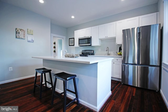 kitchen featuring white cabinetry, stainless steel appliances, dark hardwood / wood-style floors, and a kitchen island