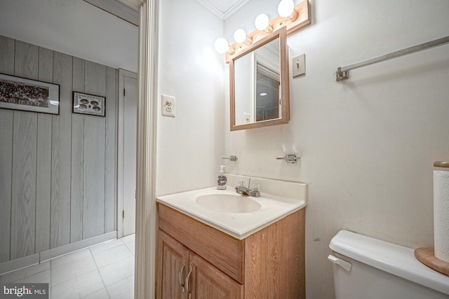 bathroom with vanity, toilet, and wood walls