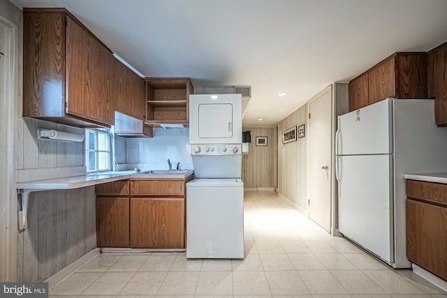 kitchen with stacked washing maching and dryer, sink, and white fridge