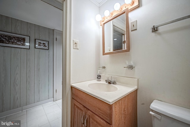 bathroom with vanity, wooden walls, and toilet