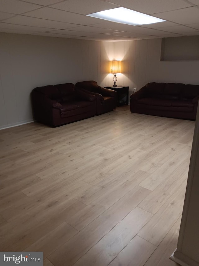 living room with a paneled ceiling and light hardwood / wood-style floors