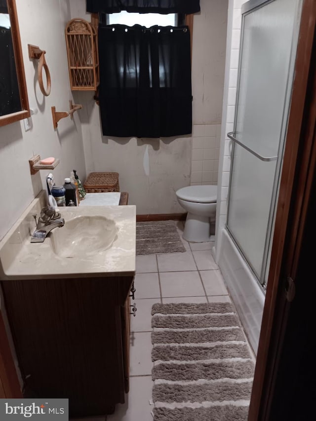 full bathroom featuring tile patterned floors, toilet, vanity, and bath / shower combo with glass door