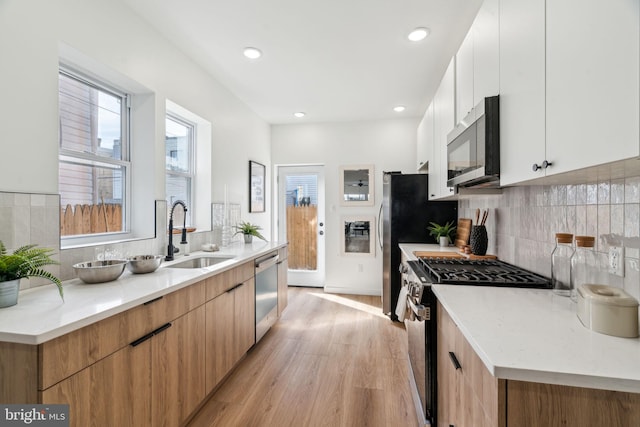 kitchen featuring sink, appliances with stainless steel finishes, white cabinetry, a wealth of natural light, and light wood-type flooring