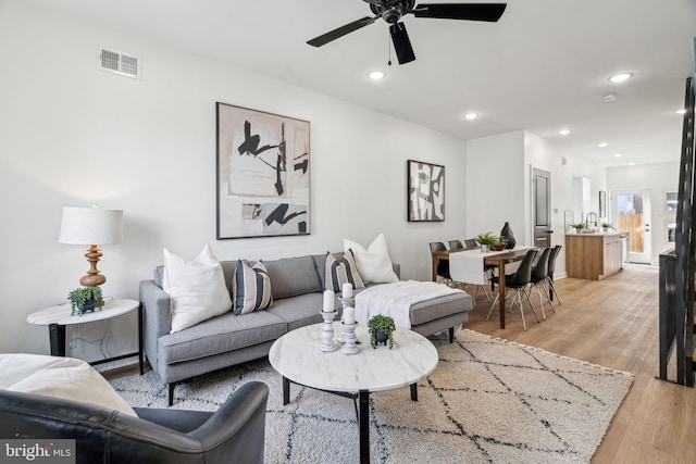 living room with ceiling fan, sink, and light hardwood / wood-style floors