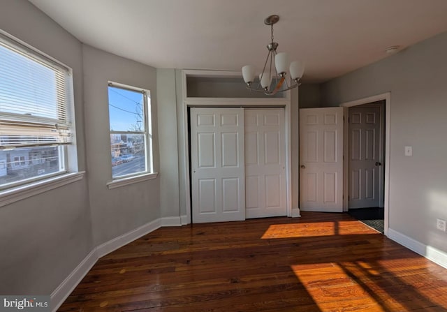 unfurnished bedroom featuring dark wood-type flooring, a chandelier, and a closet