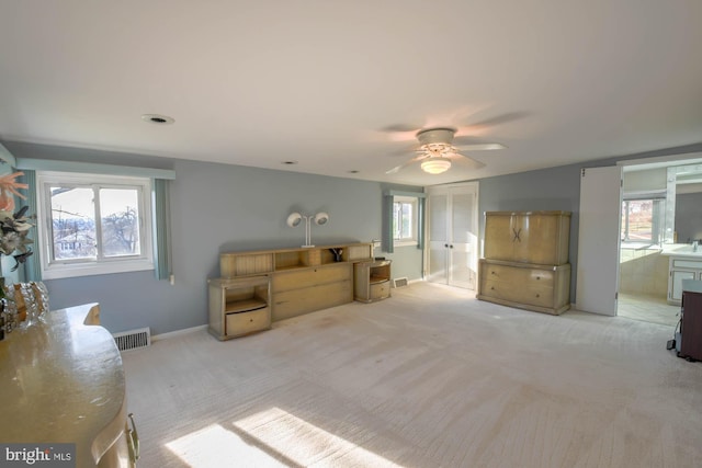 living room with ceiling fan, light colored carpet, and a healthy amount of sunlight