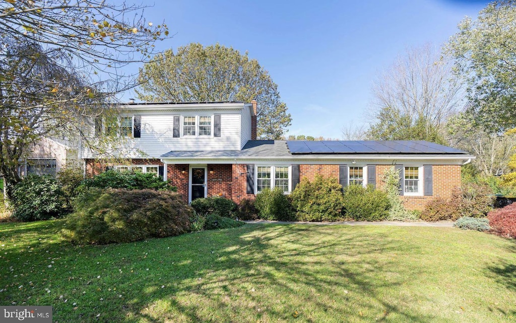 view of front property featuring a front lawn and solar panels