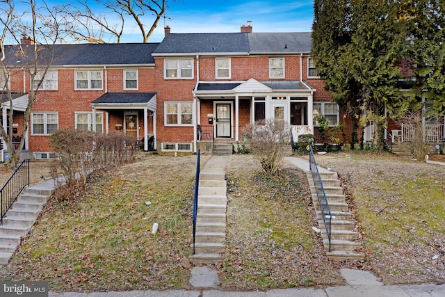 townhome / multi-family property with stairs, brick siding, and a chimney