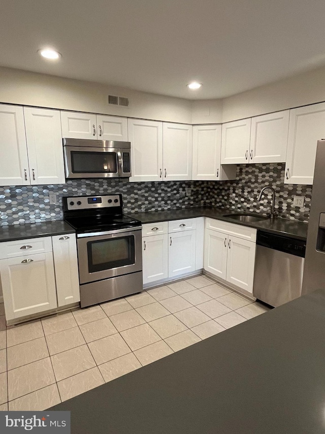 kitchen with sink, appliances with stainless steel finishes, backsplash, white cabinets, and light tile patterned flooring