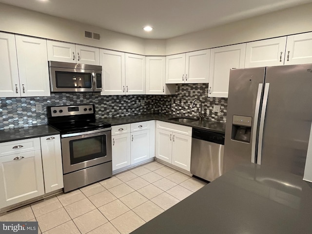 kitchen featuring appliances with stainless steel finishes, sink, white cabinets, backsplash, and light tile patterned floors