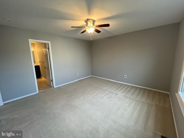 unfurnished bedroom with ceiling fan, connected bathroom, and carpet flooring