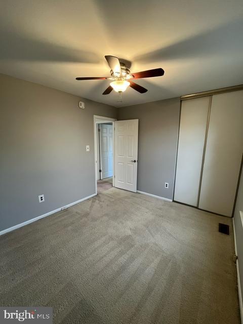 unfurnished bedroom with ceiling fan, carpet flooring, and a closet