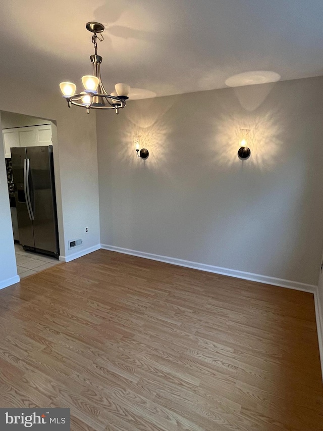 unfurnished dining area featuring light hardwood / wood-style floors and a notable chandelier