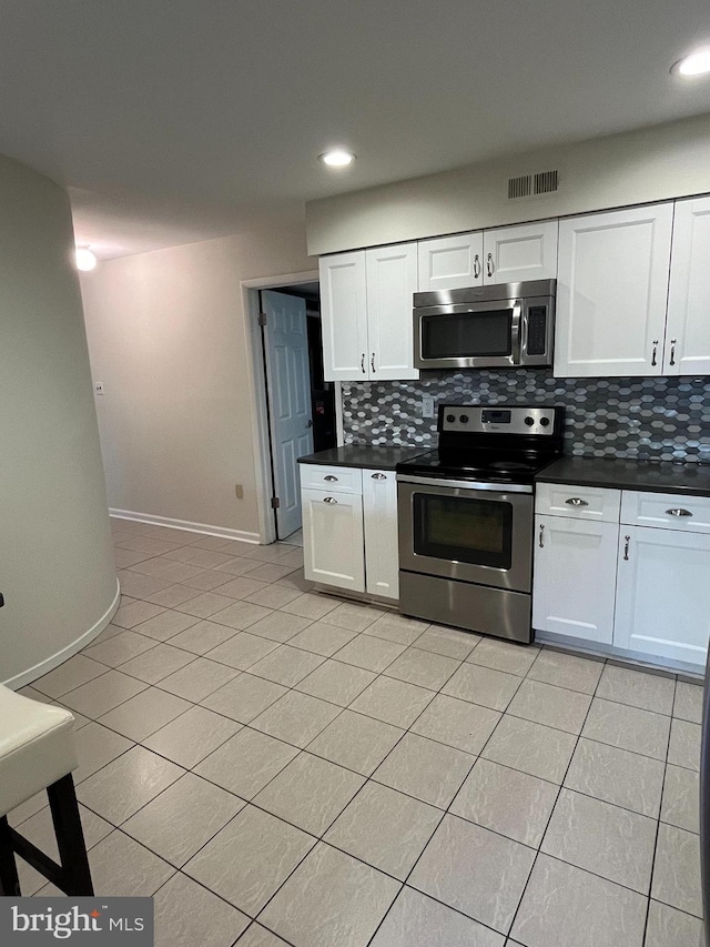 kitchen featuring white cabinetry, appliances with stainless steel finishes, light tile patterned flooring, and decorative backsplash