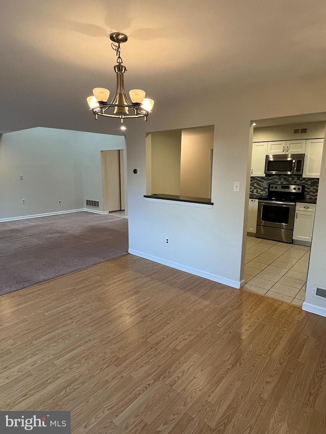 unfurnished living room with a notable chandelier and light hardwood / wood-style floors