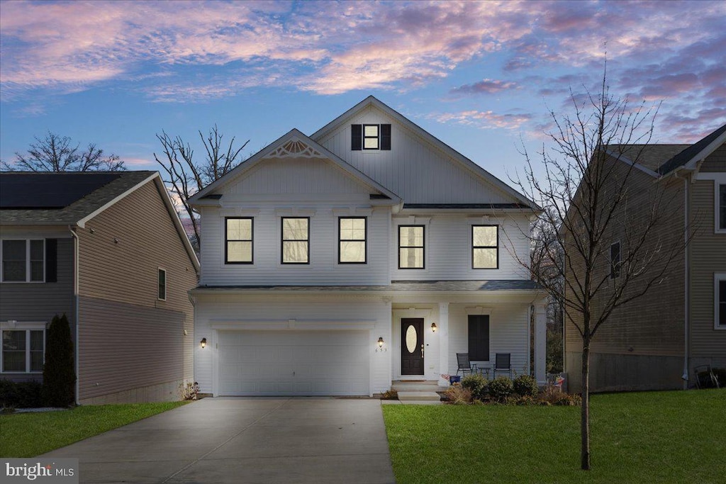 view of front facade featuring a garage, a lawn, and covered porch