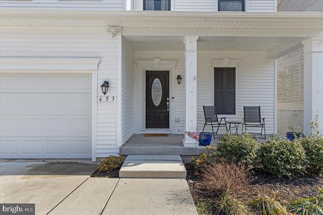 view of exterior entry with a porch and a garage