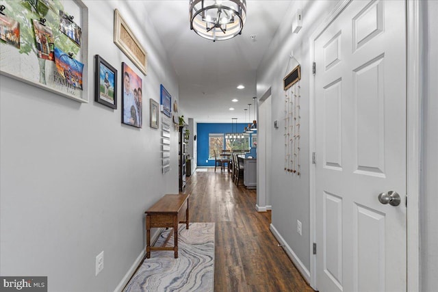 hallway featuring dark hardwood / wood-style floors and an inviting chandelier