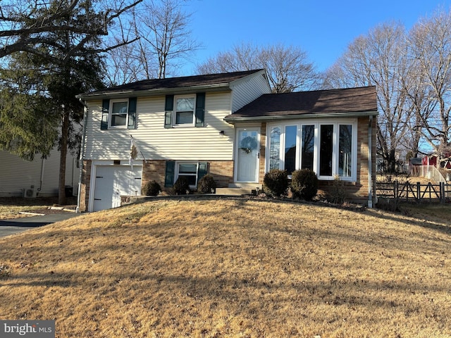 tri-level home featuring a garage, central AC unit, and a front yard