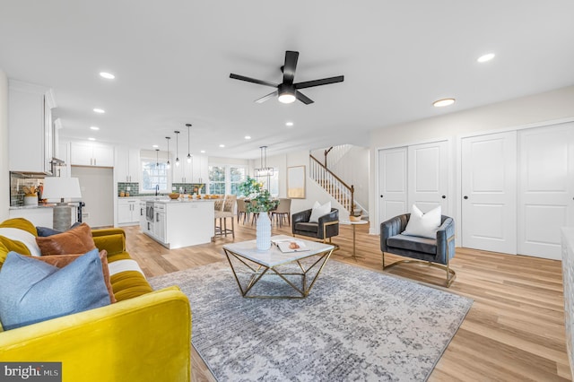 living room featuring ceiling fan, sink, and light wood-type flooring