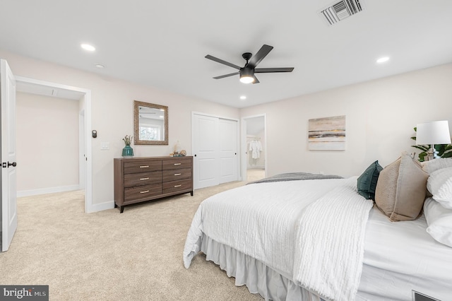 bedroom featuring ensuite bathroom, light colored carpet, ceiling fan, and a closet