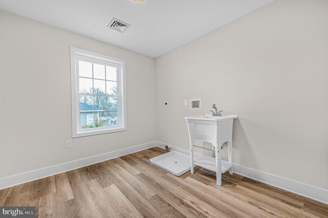 washroom with hookup for a washing machine, hookup for an electric dryer, and light wood-type flooring