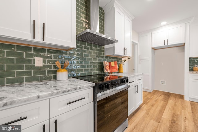 kitchen with white cabinetry, range with electric cooktop, light stone countertops, light hardwood / wood-style floors, and wall chimney exhaust hood