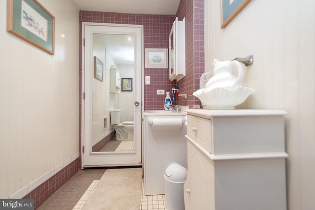 bathroom with tile patterned flooring, vanity, tile walls, and toilet