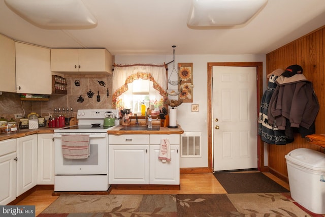 kitchen with white cabinetry, light hardwood / wood-style flooring, decorative backsplash, and electric stove