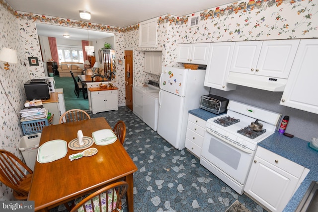 kitchen with white cabinets, white appliances, and washing machine and clothes dryer