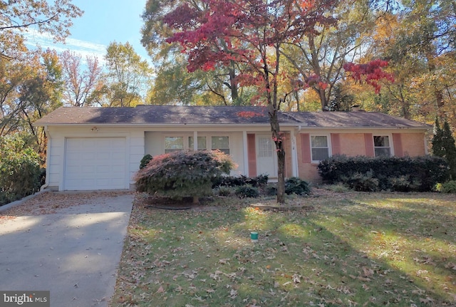 single story home featuring an attached garage, concrete driveway, and a front yard