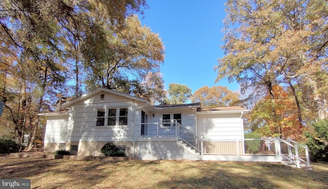 view of front of property featuring a deck, stairs, and a front lawn