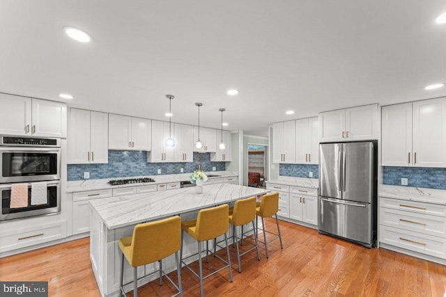 kitchen with stainless steel appliances, white cabinetry, a breakfast bar, and decorative light fixtures