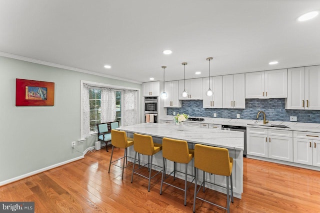 kitchen featuring a breakfast bar, appliances with stainless steel finishes, hanging light fixtures, a center island, and white cabinets