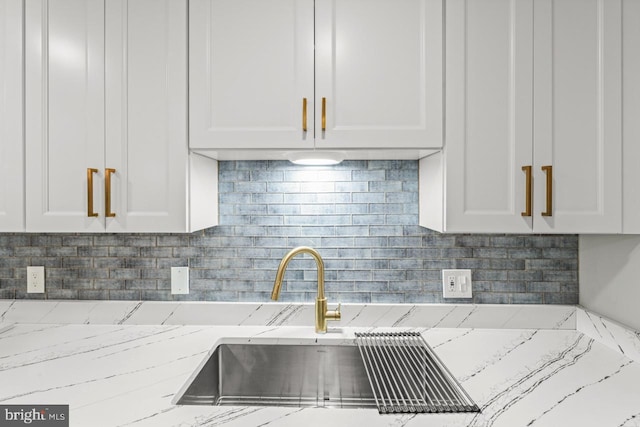 kitchen featuring light stone counters, white cabinetry, and tasteful backsplash