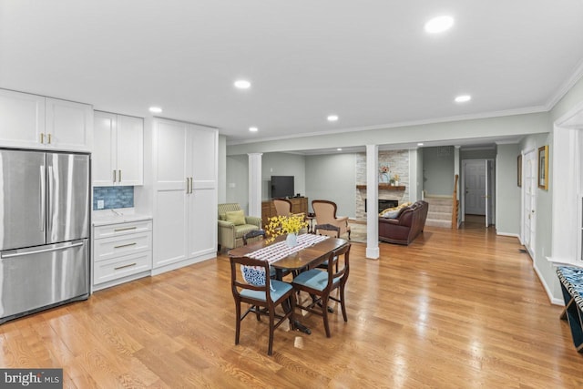 dining area with crown molding, a fireplace, and light hardwood / wood-style floors