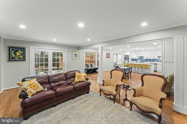 living room with ornamental molding, french doors, and light wood-type flooring