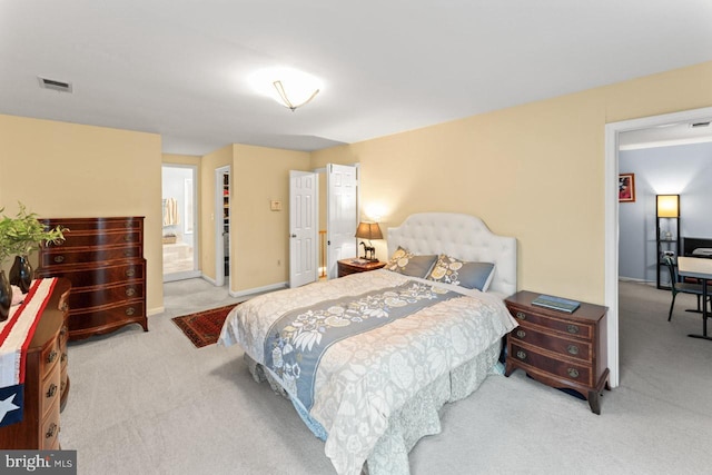 bedroom featuring connected bathroom and light carpet